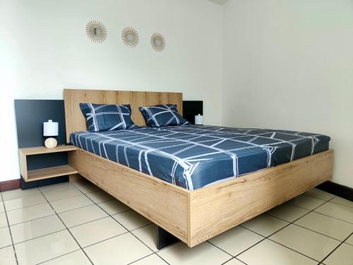 a bedroom with a large wooden bed with blue sheets at Appartement T2 - Sainte-Marie - 10 min de l'aéroport in Sainte-Marie