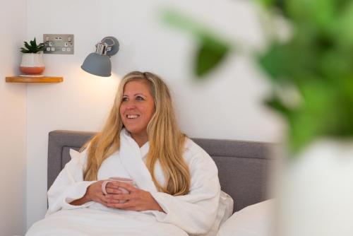 a woman sitting in a chair in a towel at Bonnie Barns - Adults Only Luxury Lodges with hot tubs in Luss