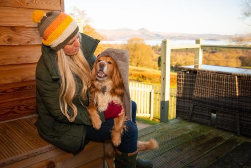 a woman sitting on a bench holding a dog at Bonnie Barns - Adults Only Luxury Lodges with hot tubs in Luss