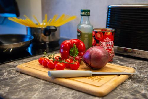 a cutting board with tomatoes and a knife on a counter at Bonnie Barns - Adults Only Luxury Lodges with hot tubs in Luss
