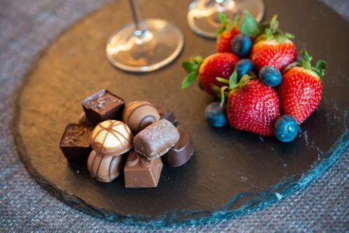 a chocolate cake with strawberries and blueberries on a plate at Bonnie Barns - Adults Only Luxury Lodges with hot tubs in Luss