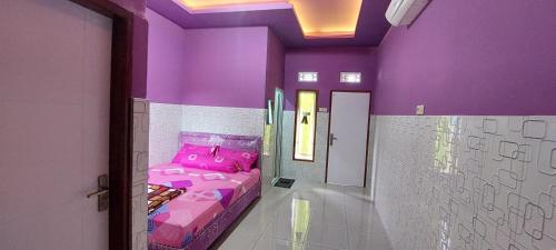 a room with a bed in a purple room at Villa Dono in Pasuruan
