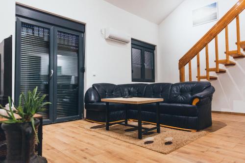 ein Wohnzimmer mit einem schwarzen Ledersofa und einem Tisch in der Unterkunft Backspace Apartments in Vršac