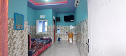 a bathroom with blue walls and a bed in it at Villa Dono in Pasuruan