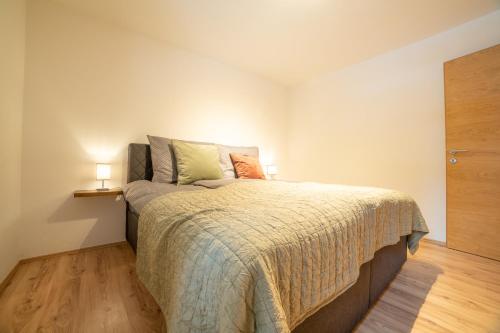 a bedroom with a large bed with two lamps on it at Ferienwohnung am Wald in Waidring