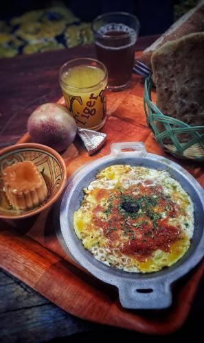a table with a plate of omelet and other food on it at Hike and Chill Homestay in Tinerhir