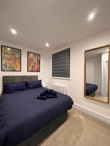 a bedroom with a blue bed and a mirror at Star London Finchley Lane 2-Bed Oasis with Garden in Hendon