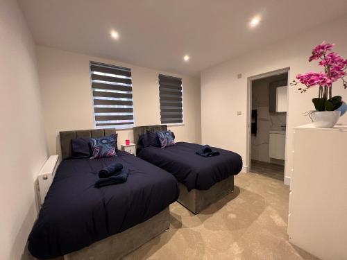 2 bedden in een slaapkamer met paarse kussens bij Star London Finchley Lane 2-Bed Oasis with Garden in Hendon