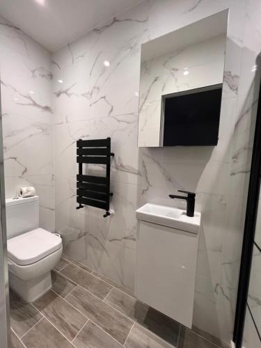 een witte badkamer met een toilet en een wastafel bij Star London Finchley Lane 2-Bed Oasis with Garden in Hendon