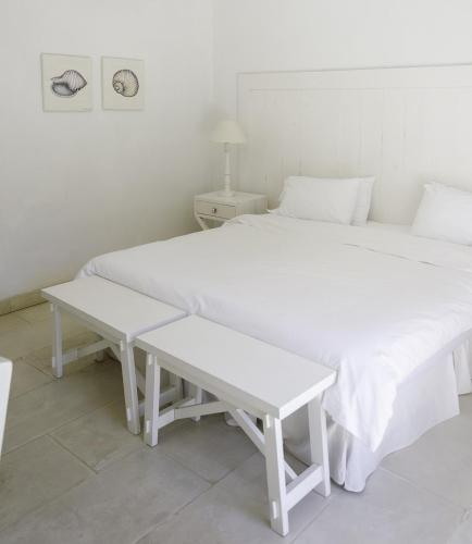 a white bedroom with two beds and a table at Kalá Hotel Boutique in Punta del Este