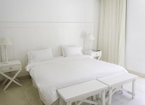 a white bedroom with a large bed and two night stands at Kalá Hotel Boutique in Punta del Este
