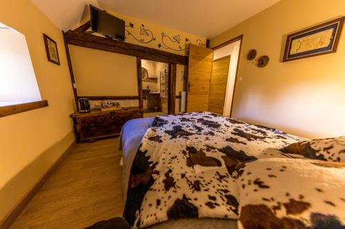 1 dormitorio con cama con motivos de vaca y lavamanos en Domaine de la Ferté Clairbois en Sainte-Suzanne