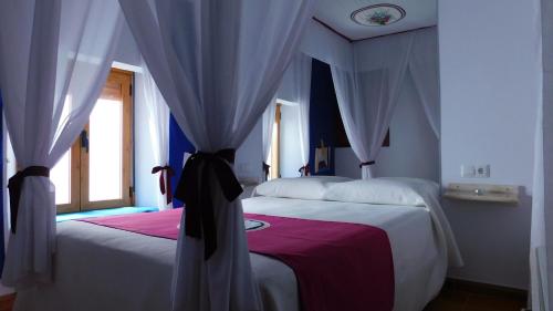 a bedroom with two beds with curtains and a window at Casa de la Abuela Pepa in Zafarraya