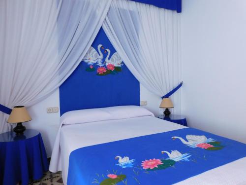 ein blau-weißes Schlafzimmer mit einem Bett und weißen Vorhängen in der Unterkunft Casa de la Abuela Pepa in Zafarraya