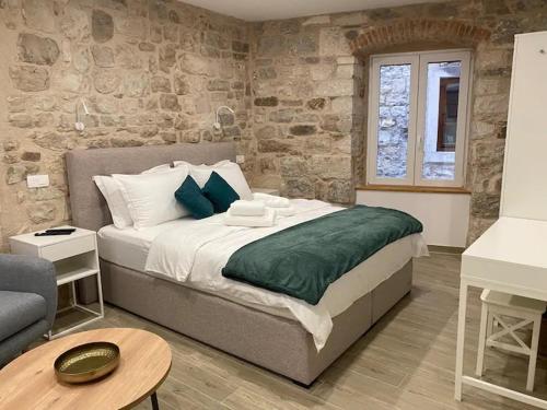 a bedroom with a large bed and a stone wall at Cloe Apartment in Split