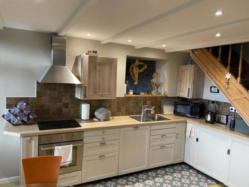 une cuisine avec un évier et une cuisinière four supérieur dans l'établissement Gîte Est de la pointe d'Agon 4 convives, à Agon-Coutainville