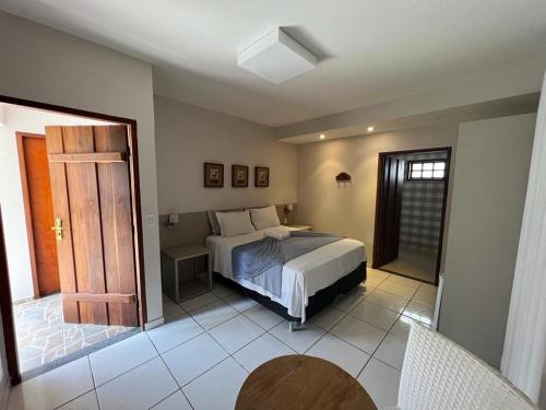 1 dormitorio con 1 cama y puerta abierta en Pousada Canto do Sabiá - Pirenópolis en Pirenópolis