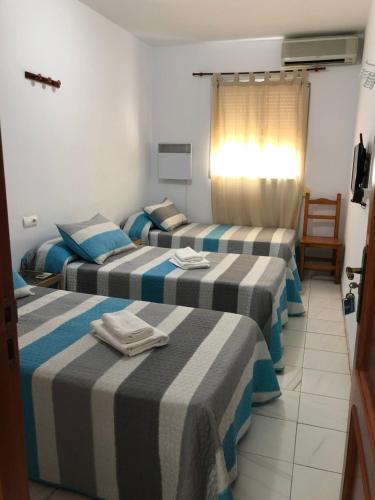 Tres camas en una habitación de hotel con toallas. en Ochomin Hostel, en San Martín del Tesorillo
