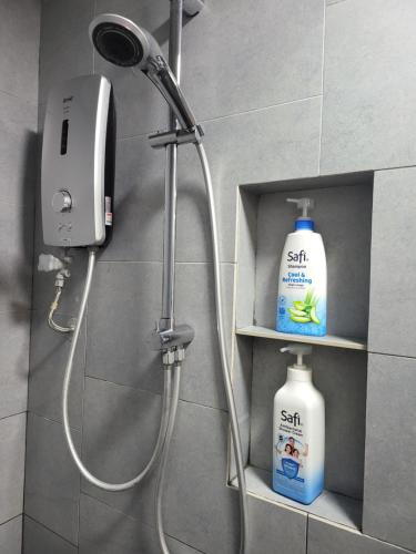 eine Dusche mit Duschkopf und zwei Flaschen Seife in der Unterkunft Kota Kinabalu Jesselton Quay Sea View with washing machine in Kota Kinabalu