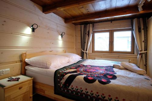 a bedroom with a bed in a wooden cabin at Domeczek Góralski Zakopane in Zakopane