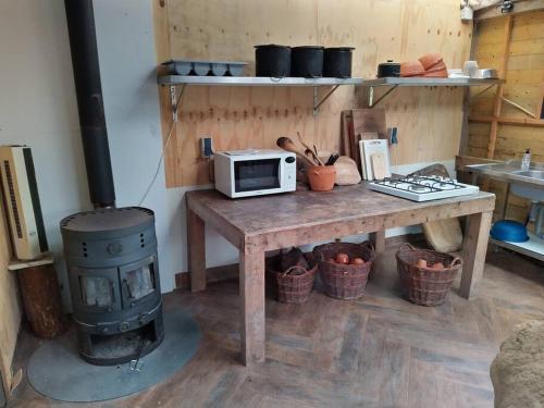 een keuken met een tafel, een magnetron en een fornuis bij Uniek overnachten in de prehistorie in Lelystad
