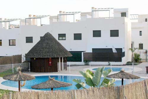 une piscine avec des parasols et un bâtiment dans l'établissement Home of the Sun - Luminoso adosado con vistas al mar y a 2 km de la playa, à Vélez-Málaga