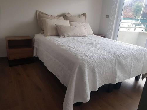 a bed with a white comforter and a window at Hermoso departamento completamente equipado in Osorno