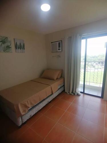 a bedroom with a bed in a room with a window at Furnished 2Br Condo With Balcony in Cagayan de Oro
