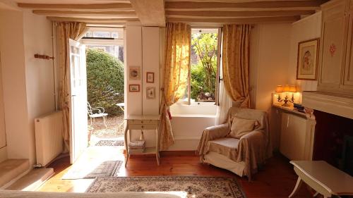 uma sala de estar com uma cadeira e uma janela em A l'Ombre du Tilleul em Giverny