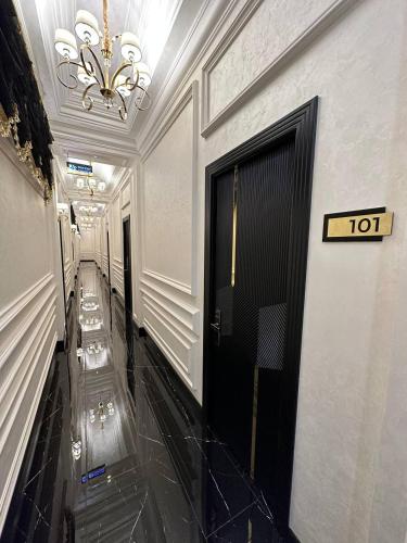 a hallway with a black door and a chandelier at East Star Hotel in Samarkand