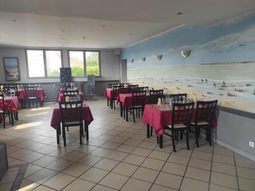 un restaurant avec des tables et des chaises ainsi qu'une fresque murale représentant la plage. dans l'établissement le saint firmin, au Crotoy
