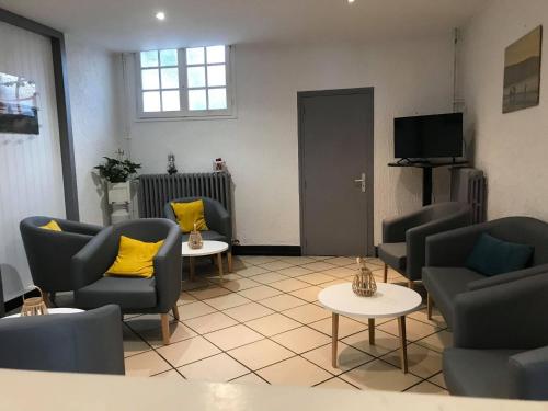 a living room with chairs and tables and a tv at le saint firmin in Le Crotoy