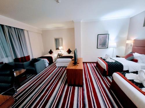 ドーハにあるWonder Palace Hotel Qatarのベッド2台とリビングルームが備わるホテルルームです。