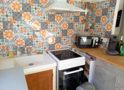 Il comprend une cuisine équipée d'une cuisinière. - un four à micro-ondes dans l'établissement Maison de plage ambiance rock et zen, à Saint Pierre La Mer
