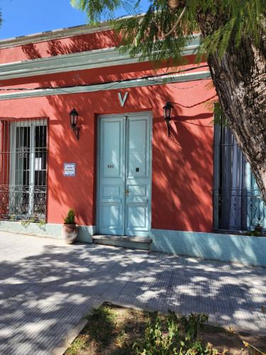 a red building with a blue door in front at Casa Victoria in Colonia del Sacramento