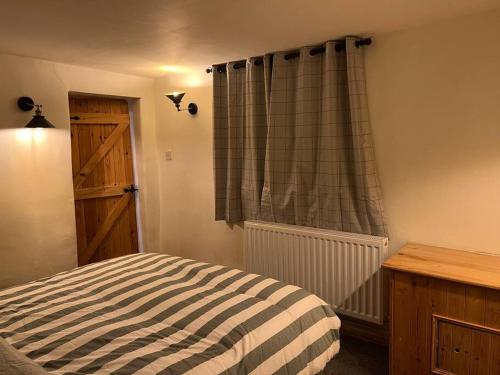 1 dormitorio con cama y ventana con cortina en The Barn Behind en Castleton