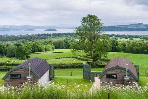 two barns in a field with a lake at Bonnie Barns - Adults Only Luxury Lodges with hot tubs in Luss