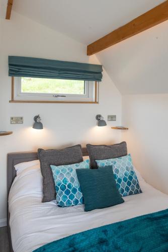 a bedroom with a bed with blue and white pillows at Bonnie Barns - Adults Only Luxury Lodges with hot tubs in Luss