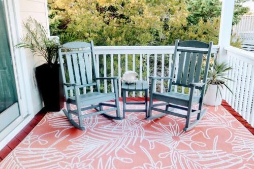 2 chaises assises sur une terrasse couverte avec un tapis dans l'établissement Lake Front Modern Beach House-Hatteras Island, à Avon