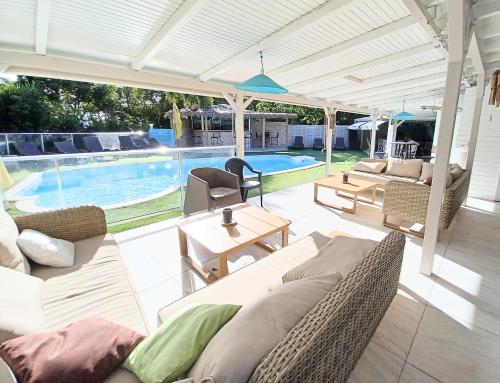 a patio with couches and a swimming pool at La Rose du Bresil Marie-Galante in Capesterre-de-Marie-Galante