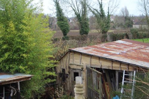 an old building with a rusty tin roof at maison d'artiste accès jardin in Maubeuge