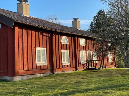 a large red building with a grass yard next to it at Hova Prästgård Bed & Breakfast in Hova