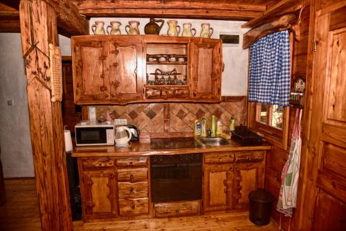 a kitchen with wooden cabinets and a sink and a microwave at Guesthouse Peto in Novi Kneževac