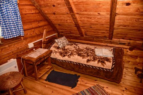 a room with a bed and a chair in a log cabin at Guesthouse Peto in Novi Kneževac