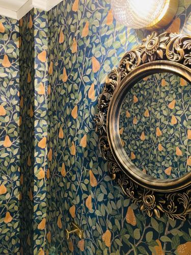 a mirror on a wall with a floral wallpaper at Hova Prästgård Bed & Breakfast in Hova