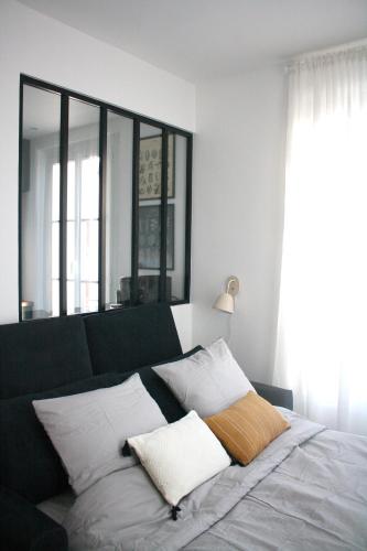 una camera da letto con un letto con cuscini bianchi di Studio neuf Paris - La Défense a Colombes