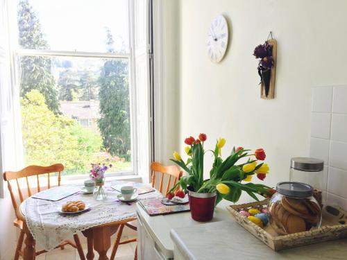 eine Küche mit einem Tisch und einem Fenster mit Blumen in der Unterkunft Grosvenor Apartments in Bath - Great for Families, Groups, Couples, 80 sq m, Parking in Bath