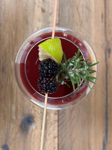 a drink with blackberries and a lime on a wooden table at Hotel Reipertingerhof in Brunico