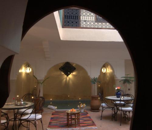 a room with tables and chairs and a pool at Riad Imilchil in Marrakesh