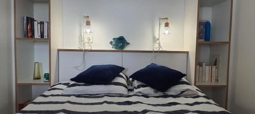 a bed with two blue pillows in a room at Vue Belle île in Quiberon
